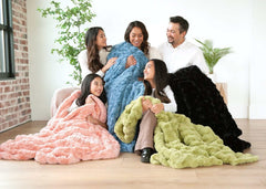 Young family sitting together while wrapped up in four different colored blankets.