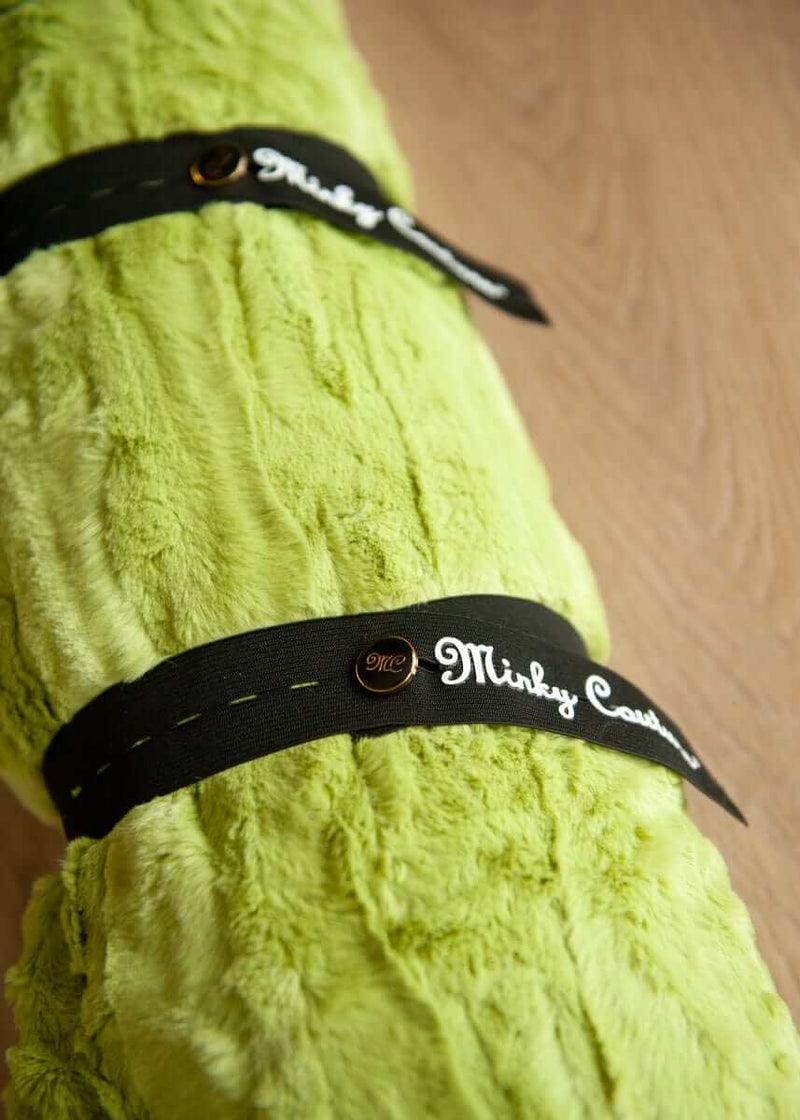 Minky Keepers securing a plush green blanket for organized storage on a wooden surface.