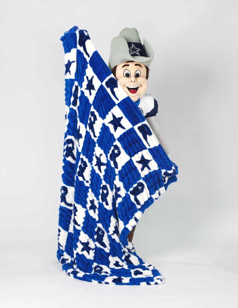 A Dallas Cowboys mascot holding up a large blue and white checkered blanket with star and cowboy boot pattern.
