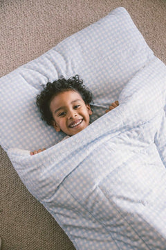Minky Couture Sleeping Bag Dusty Blue Gingham with a smiling child wrapped inside.