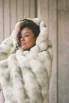 Young woman wrapped up Extreme Ultra Cloud Winter Sage weighted blanket.