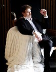 Man in a suit relaxing with the Biggest Hugs Cream weighted blanket draped over a chair, showcasing its comfort and elegance.