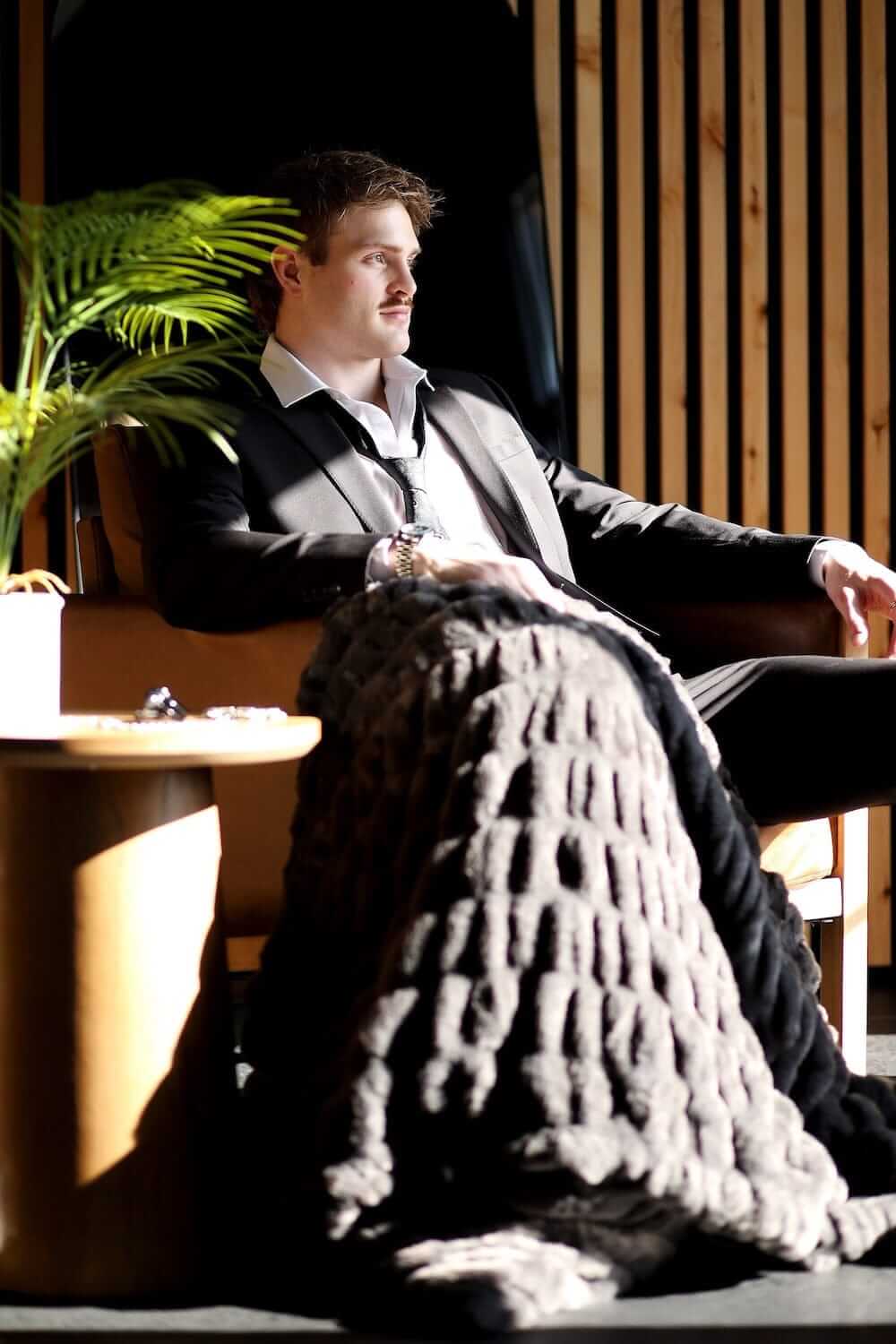 Walker Kessler Biggest Hugs Charcoal Blanket draped over a man in a stylish setting, merging luxury with comfort.