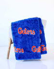 Blue University of Florida Gators plush blanket draped over a chair, featuring orange “Gators” lettering.