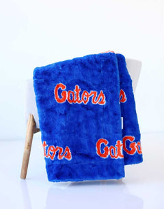 Blue University of Florida Gators plush blanket draped over a chair, featuring orange “Gators” lettering.
