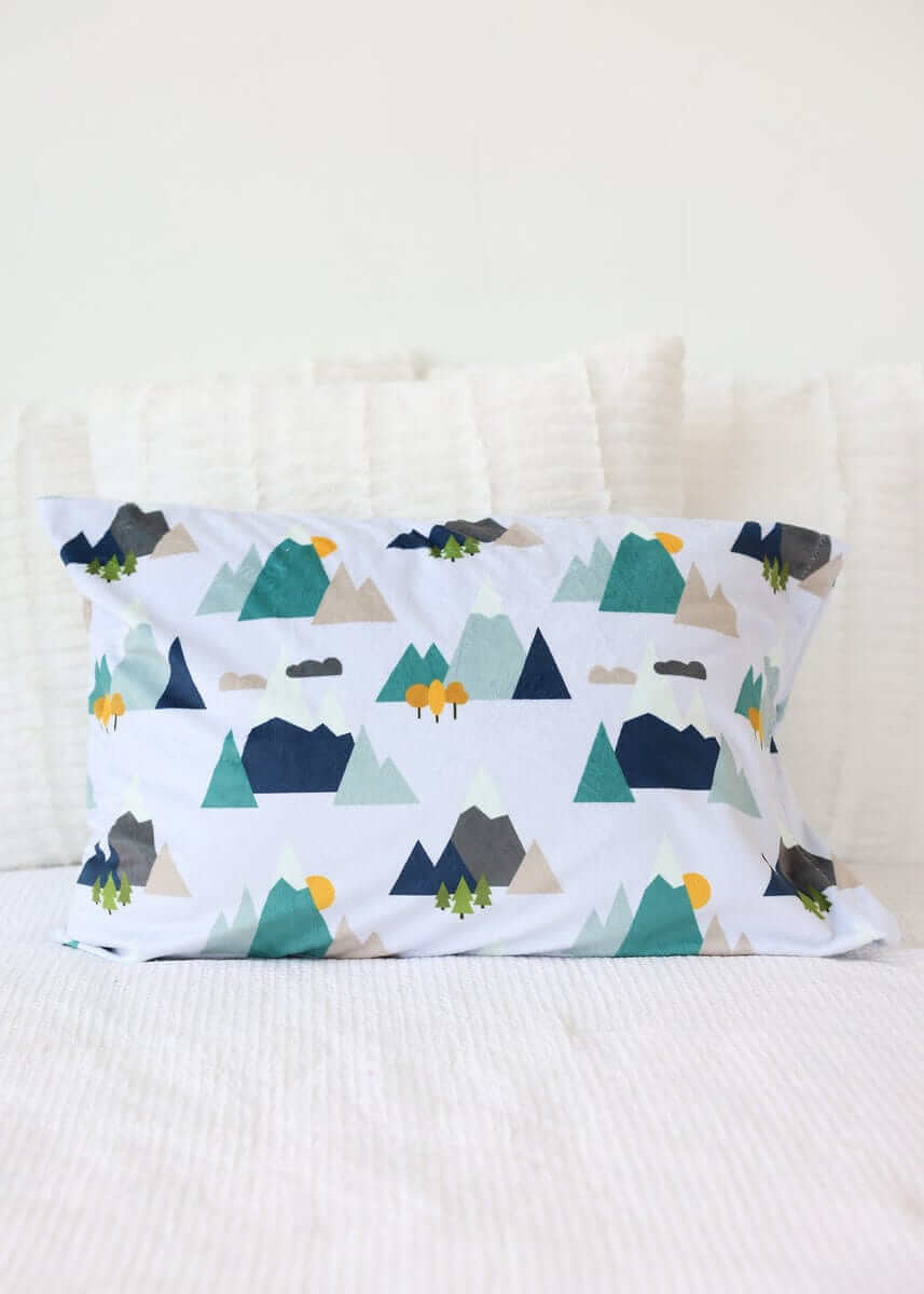 Mountain Tops Blanket featuring a colorful mountain pattern on a soft fabric pillow, perfect for cozying up.