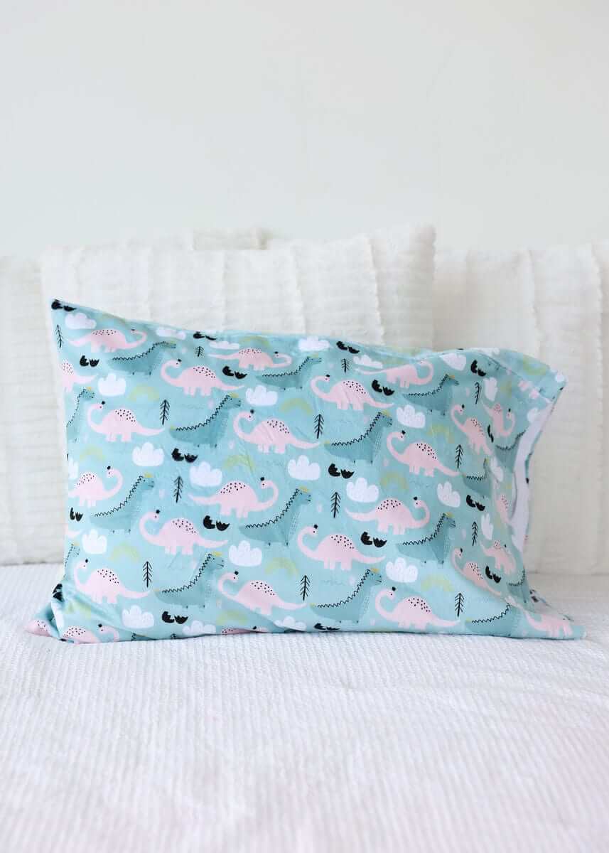 Ms. Dino Blanket with blue and pink dinosaur pattern on light blue fabric, featuring a plush backing and satin ruffle.