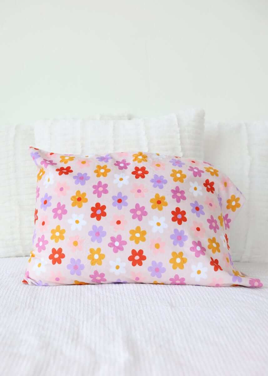 Flower Power Blanket pillow with vibrant floral design on soft pink background.