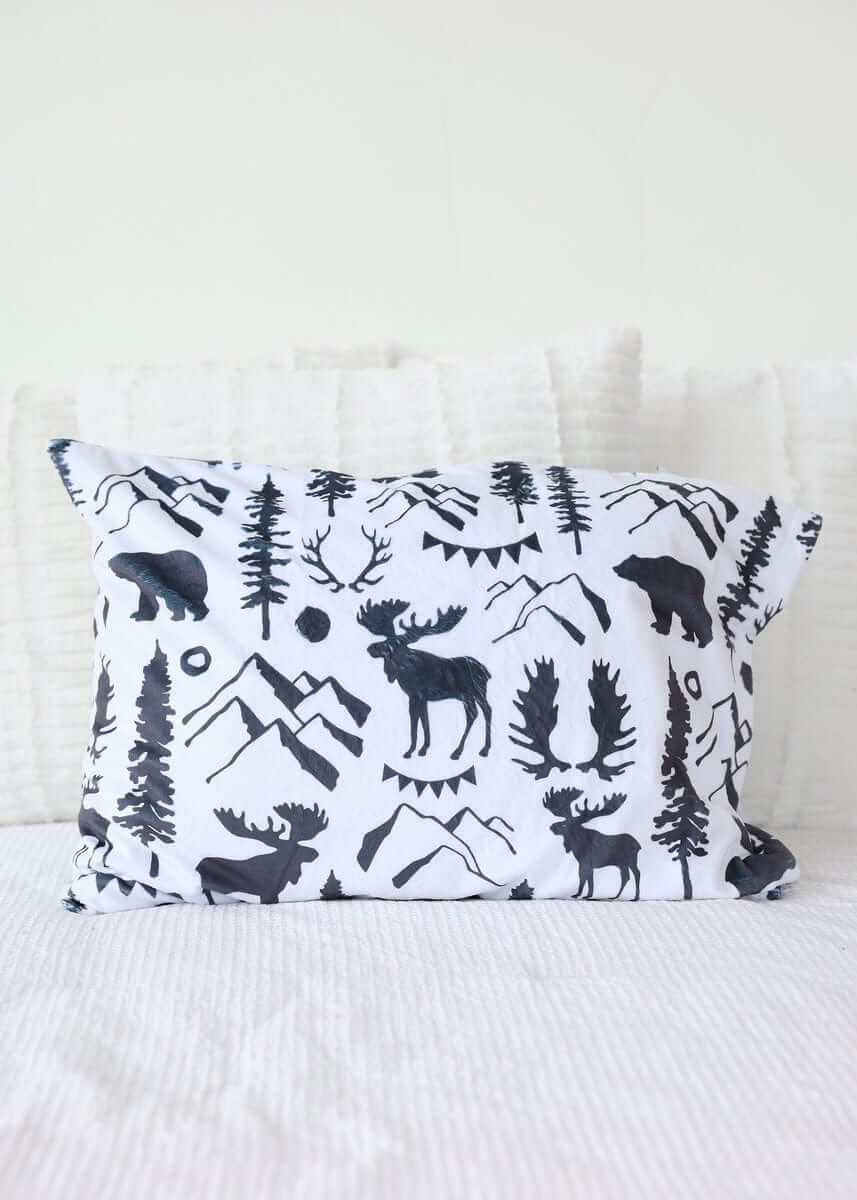 Wilderness Blanket design featuring moose, bears, and mountains on a decorative pillow.