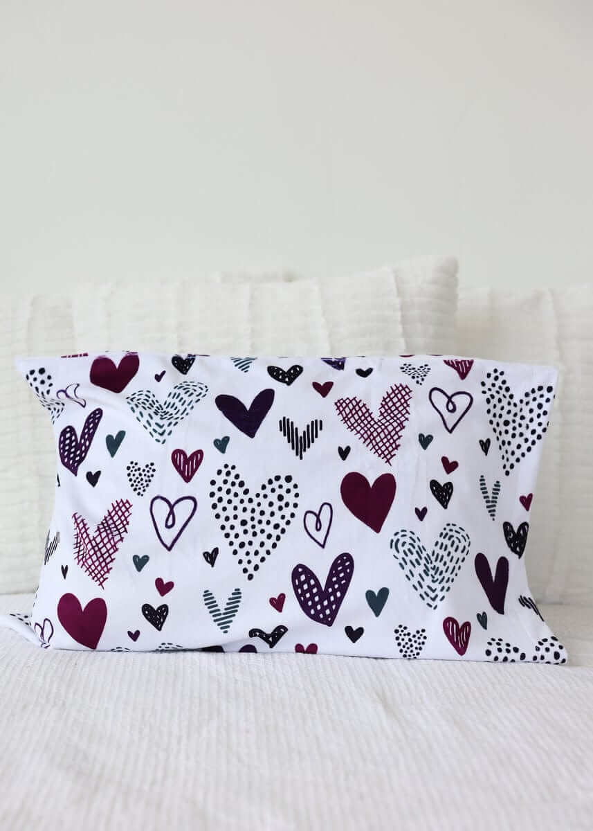 Love Notes Plum Blanket with sweet doodled hearts in purples and grays on a paper-white background.