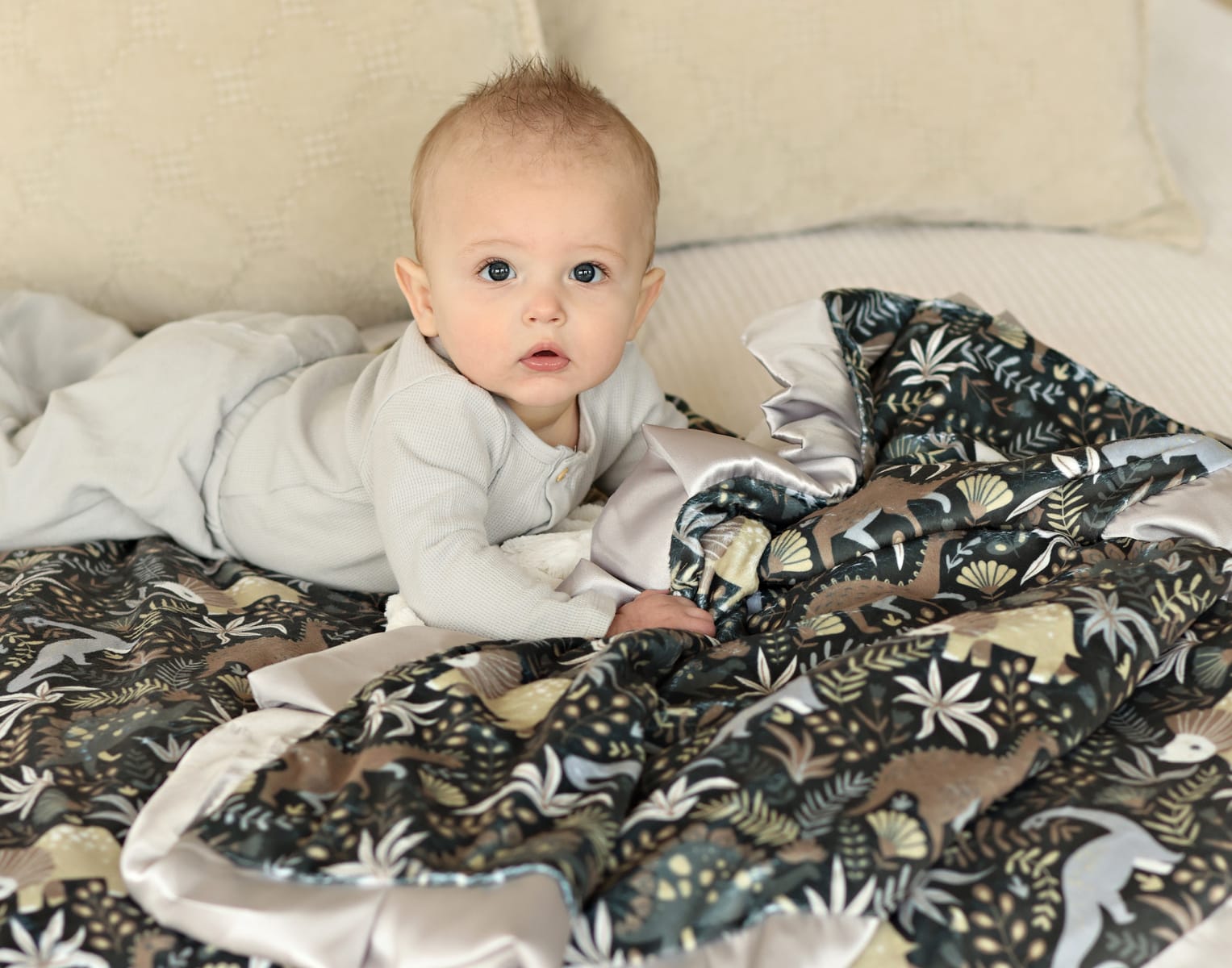 Minky Couture Gray Little Dino Blanket with a cozy baby exploring its playful dinosaur design on a soft, plush backing.