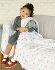 Child snuggling with Itsy Bitsy Flower Gold Blanket on a cozy couch, showcasing its delicate flower design.