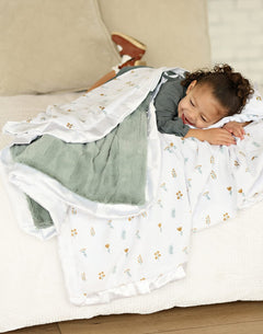Child snuggled in Itsy Bitsy Flower Gold Blanket, featuring tiny flowers on a white background with a mist plush minky backing.