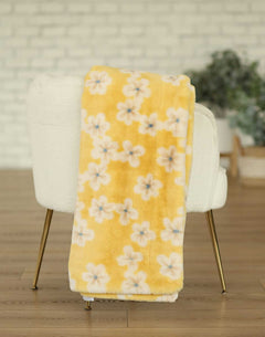 Lush Butter Yellow Floral Blanket draped over a chair, showcasing its bright floral pattern and soft texture.