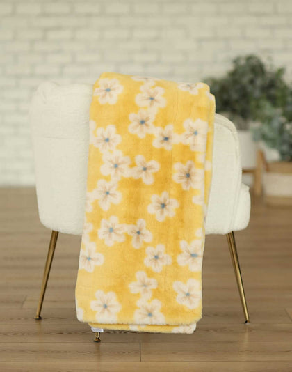 Lush Butter Yellow Floral Blanket draped over a chair, showcasing its bright floral pattern and soft texture.
