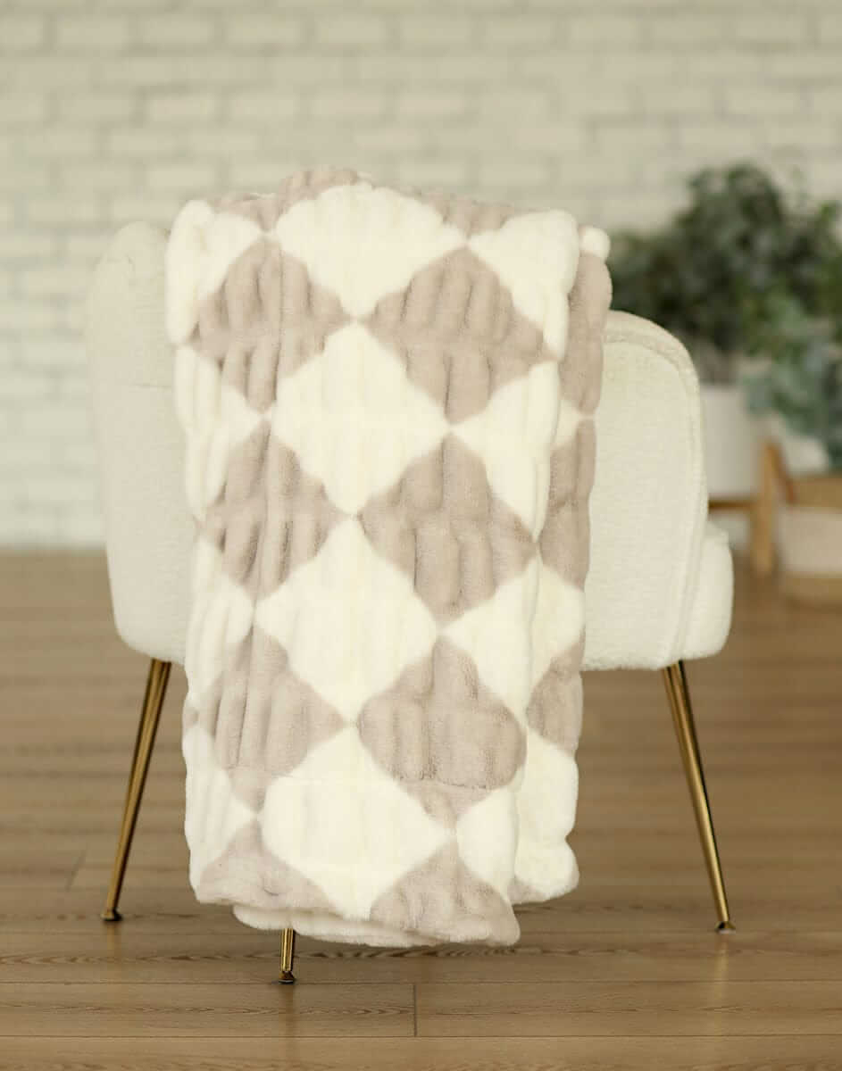 Hugs Diamond Ancient Scroll Blanket draped over a chair showcasing its diamond pattern in cream and tan tones.