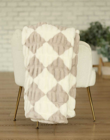 Hugs Diamond Ancient Scroll Blanket draped over a chair showcasing its diamond pattern in cream and tan tones.