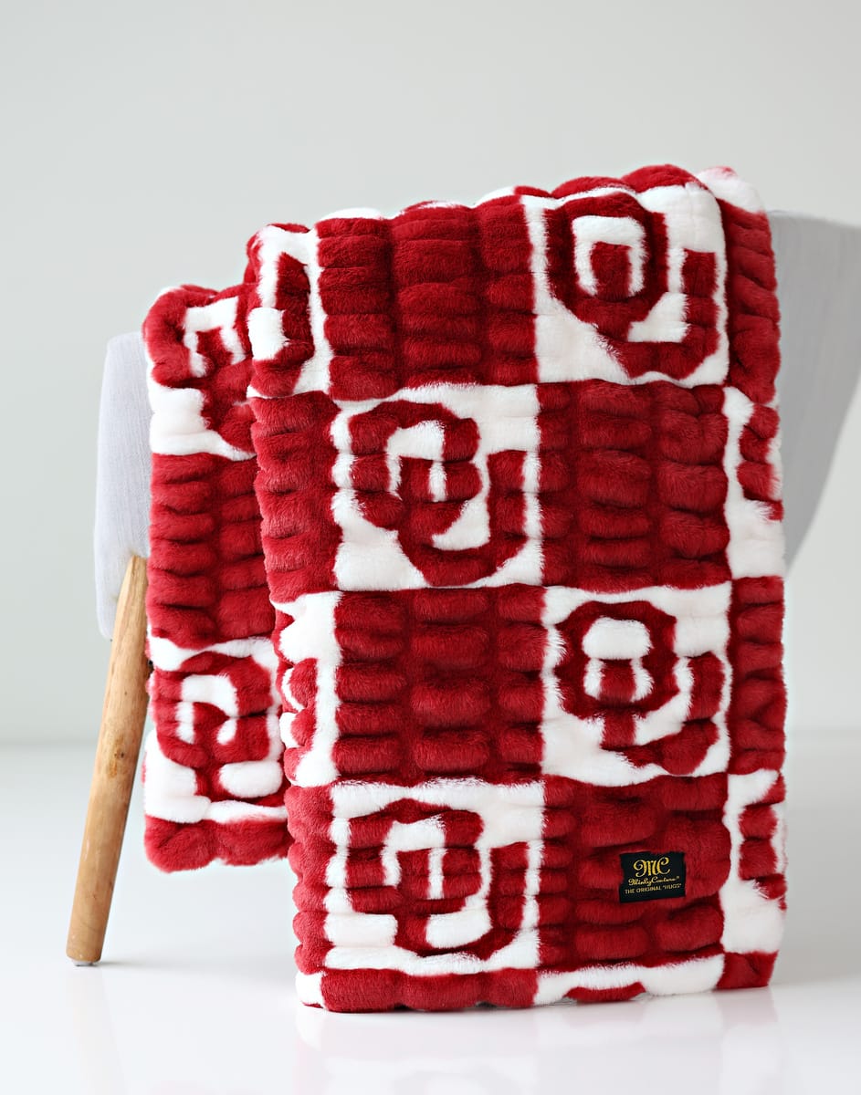 University of Oklahoma Sooners Blanket  draped on a chair, featuring a cozy red and white pattern.