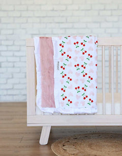 Minky Couture Cheery Cherry Blanket draped over a crib featuring cherry designs and a plush apricot backing.