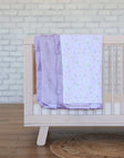 Minky Couture Itsy Bitsy Bows Blanket draped over a crib with pastel bows on white and lavender plush backing.