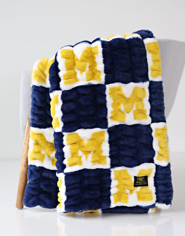 Hugs University of Michigan Wolverines Blanket in blue and maize colors with soft checkerboard design.