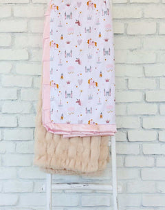 Princess Castle Blanket displayed on a chair, featuring whimsical designs of castles and unicorns with a pink satin ruffle.