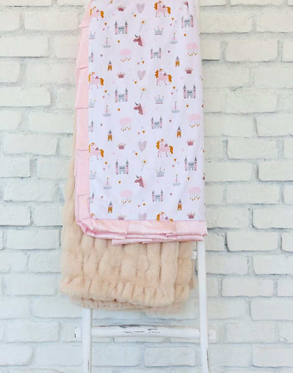 Princess Castle Blanket displayed on a chair, featuring whimsical designs of castles and unicorns with a pink satin ruffle.