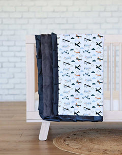 Airplane Blanket featuring small airplanes and clouds on a white background with a charcoal plush backing and satin ruffle.