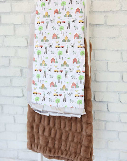 On the Farm Blanket featuring farm scenes with barns, tractors, and a plush backing for cozy comfort.