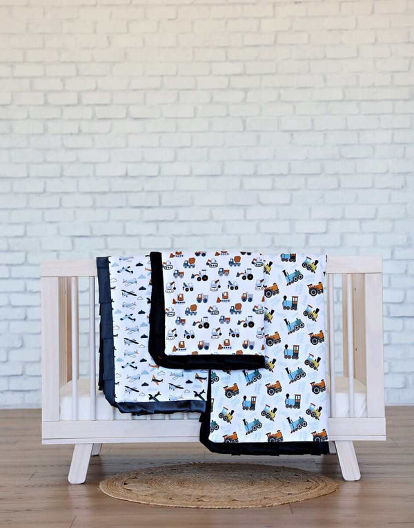Minky Couture Bulldozer Blanket featuring construction vehicles, displayed in a crib with a black satin ruffle.