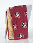 Florida State Seminoles Hooded Stadium Everywhere Blanket displayed on a chair, featuring maroon fabric with logo and plush interior.