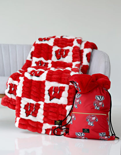 University of Wisconsin Badgers Hooded Stadium Everywhere Blanket draped over a chair with a matching backpack.