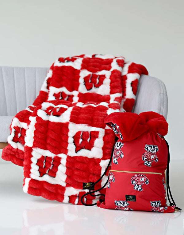 University of Wisconsin Badgers Hooded Stadium Everywhere Blanket draped over a chair with a matching backpack.
