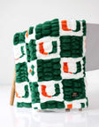 Green, white, and orange Miami Hurricanes Minky Couture blanket folded and draped over a chair, showing its textured pattern.