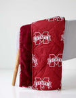 Mississippi State Everywhere Minky Couture blanket folded over a chair, showing maroon logo side and plush lining.