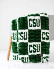 Colorado State Rams Minky Couture blanket folded over a chair, featuring green and white textured lettering pattern.
