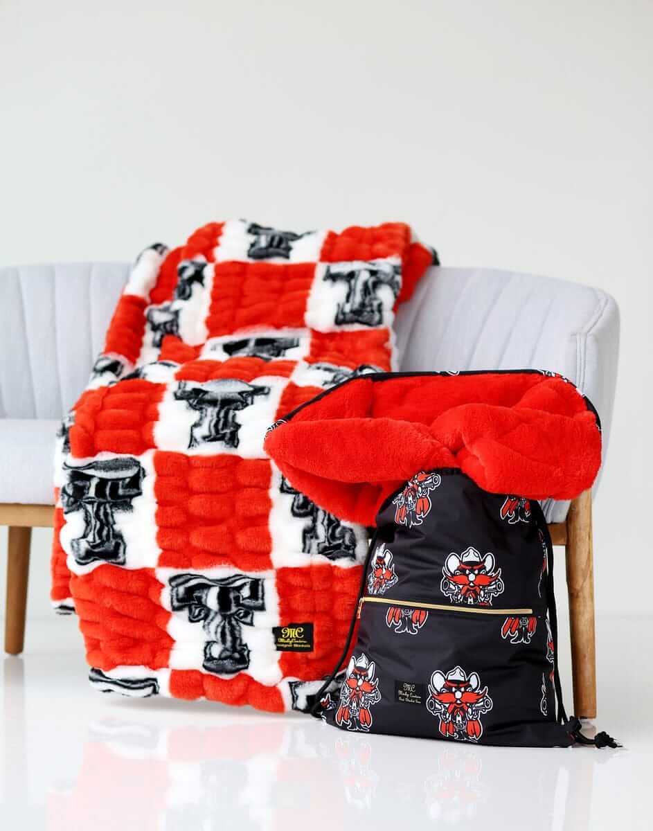 Texas Tech Raiders Minky Couture blanket on a chair with matching drawstring bag beside it.