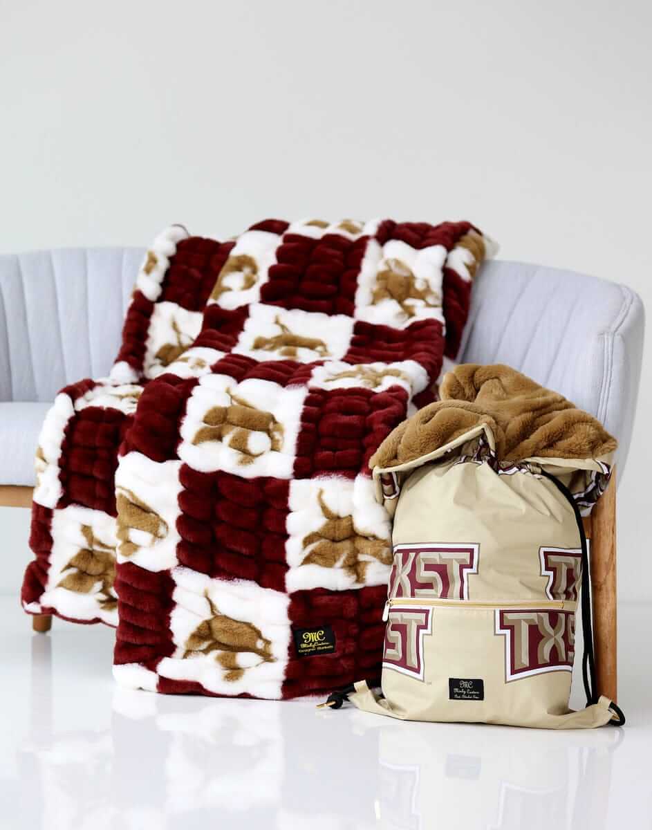 Texas Bobcats Hugs Minky Couture blanket on a chair with matching Texas State drawstring bag beside it.