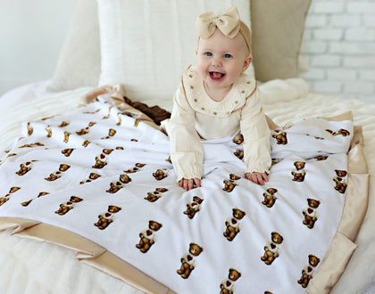 Sweetheart Bear Blanket featuring an adorable baby smiling while sitting on the blanket with bear prints.