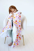 Child snuggling in the Flower Power Blanket featuring vibrant floral design and plush backing.