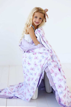 Pastel Butterfly Blanket draped over a girl with blonde hair, showcasing pink and lilac butterflies on a soft lavender background.
