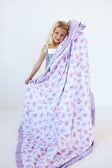 Girl smiling while holding a cozy Pastel Butterfly Blanket featuring pink and lilac butterflies on a soft white background.