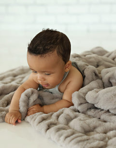 Hugs Tranquil Dove Blanket enveloping a baby in soft gray fabric, showcasing comfort and serenity.
