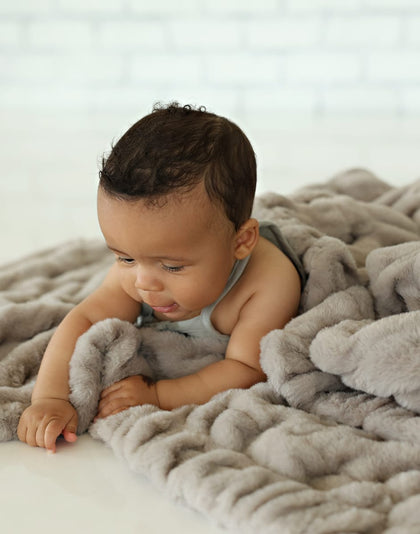 Hugs Tranquil Dove Blanket enveloping a baby in soft gray fabric, showcasing comfort and serenity.