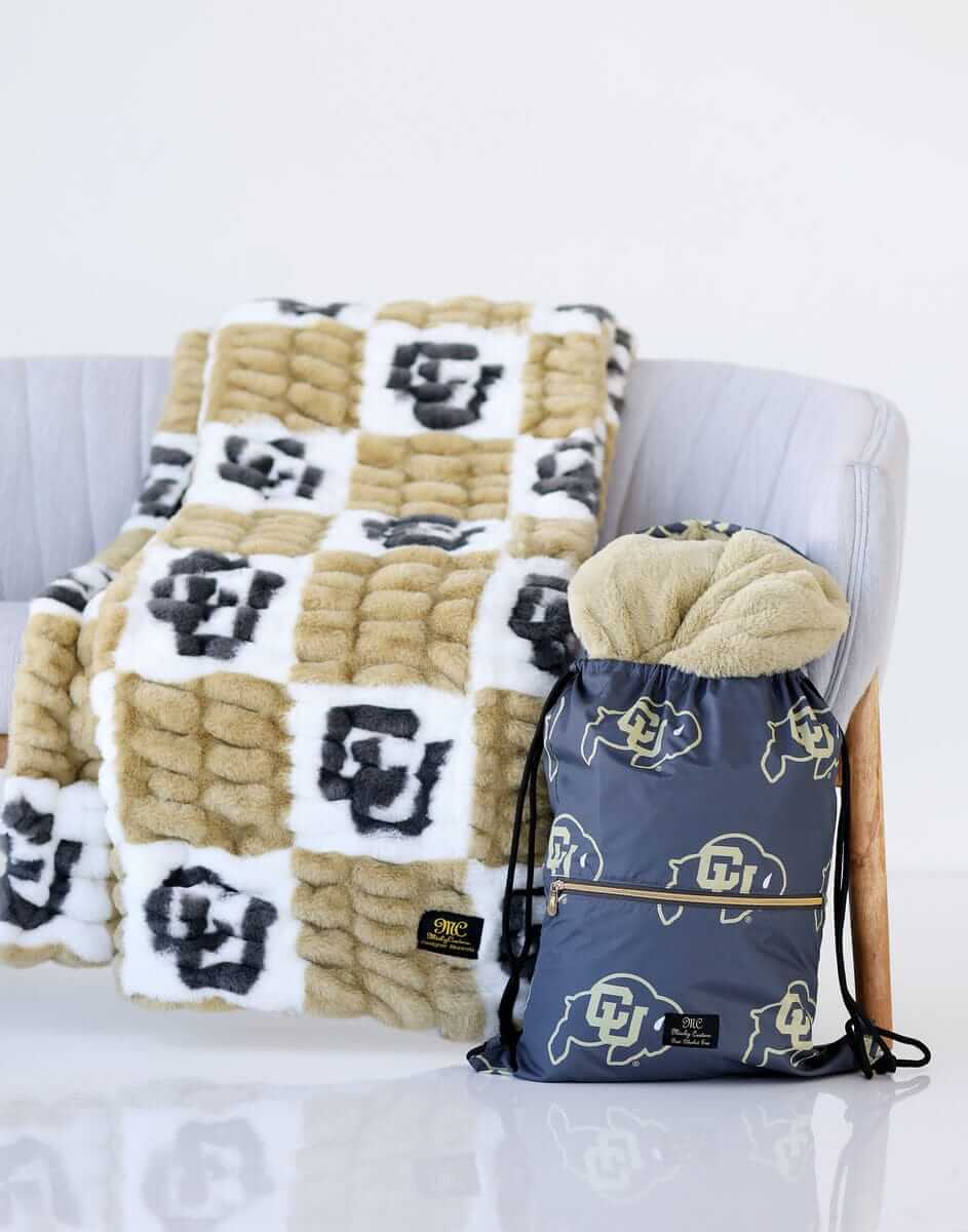 Colorado Buffaloes Blanket draped over a chair next to a matching drawstring bag featuring CU logos.