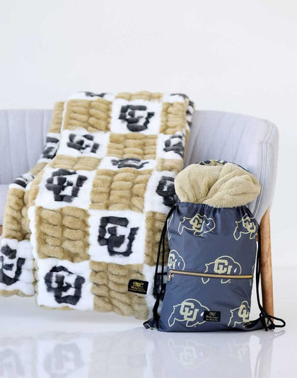 Colorado Buffaloes Blanket draped over a chair next to a matching drawstring bag featuring CU logos.