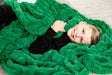 A child wrapped in the Hugs Green Blanket, showcasing its plush texture and vibrant green color.
