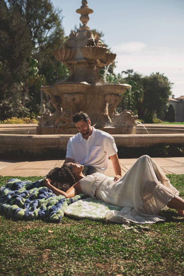 Couple enjoying a sunny day outdoors on the Minky Couture Hugs Bold Stripe Blanket near a fountain.