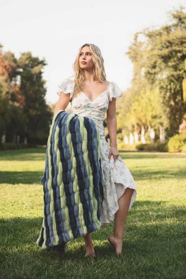 Hugs Bold Stripe Blanket showcased in the hands of a model outdoors, highlighting its vibrant stripes and cozy texture.