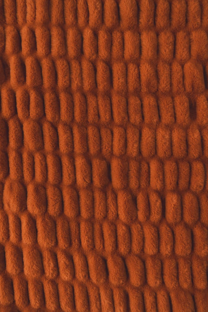 A close-up of warm rust-orange colored blanket.